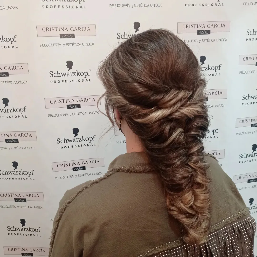 Trenza de espiga suelta delante del photocall del salón