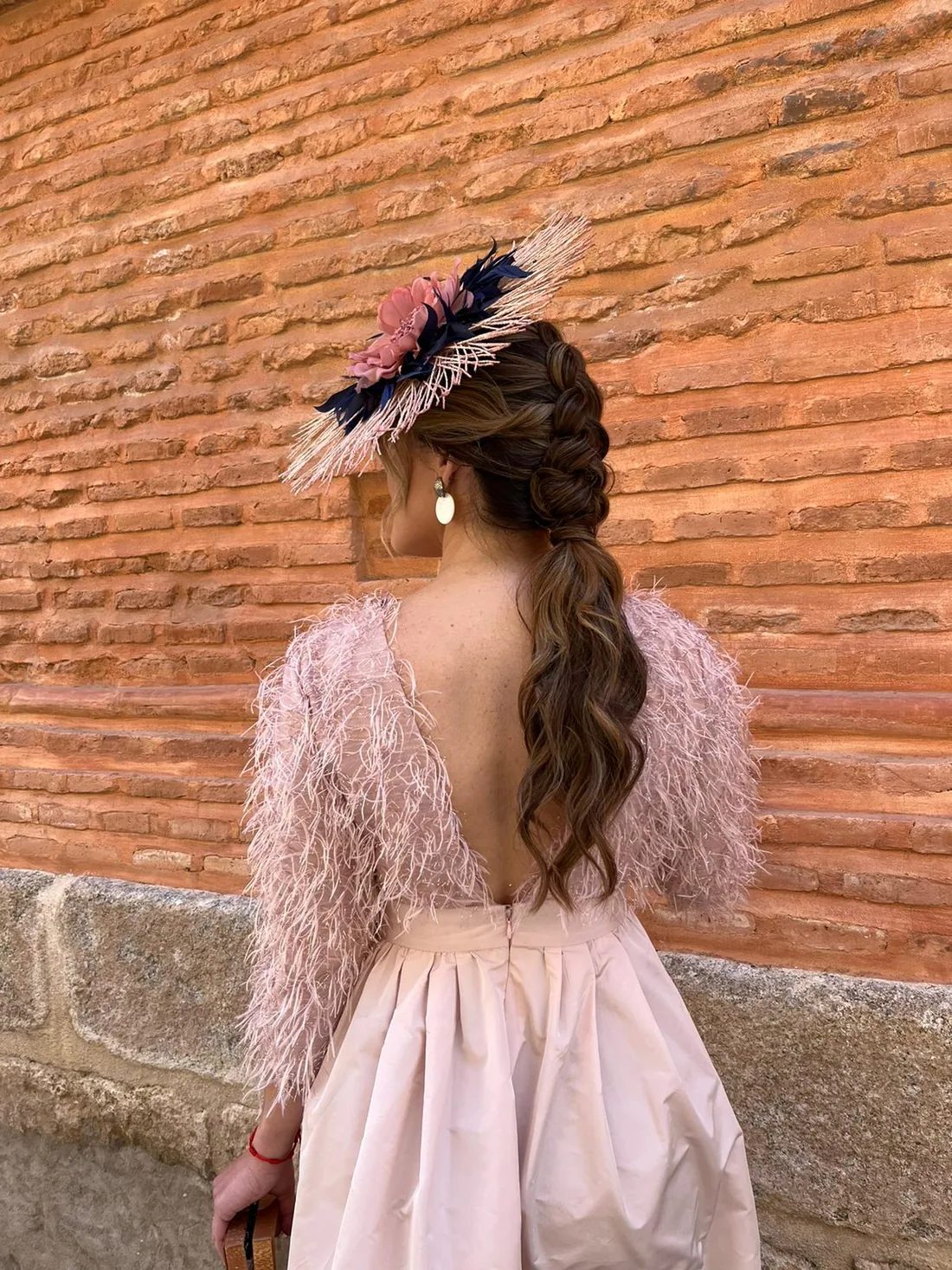 Trenza de espiga con tocado de plumas para invitada de boda