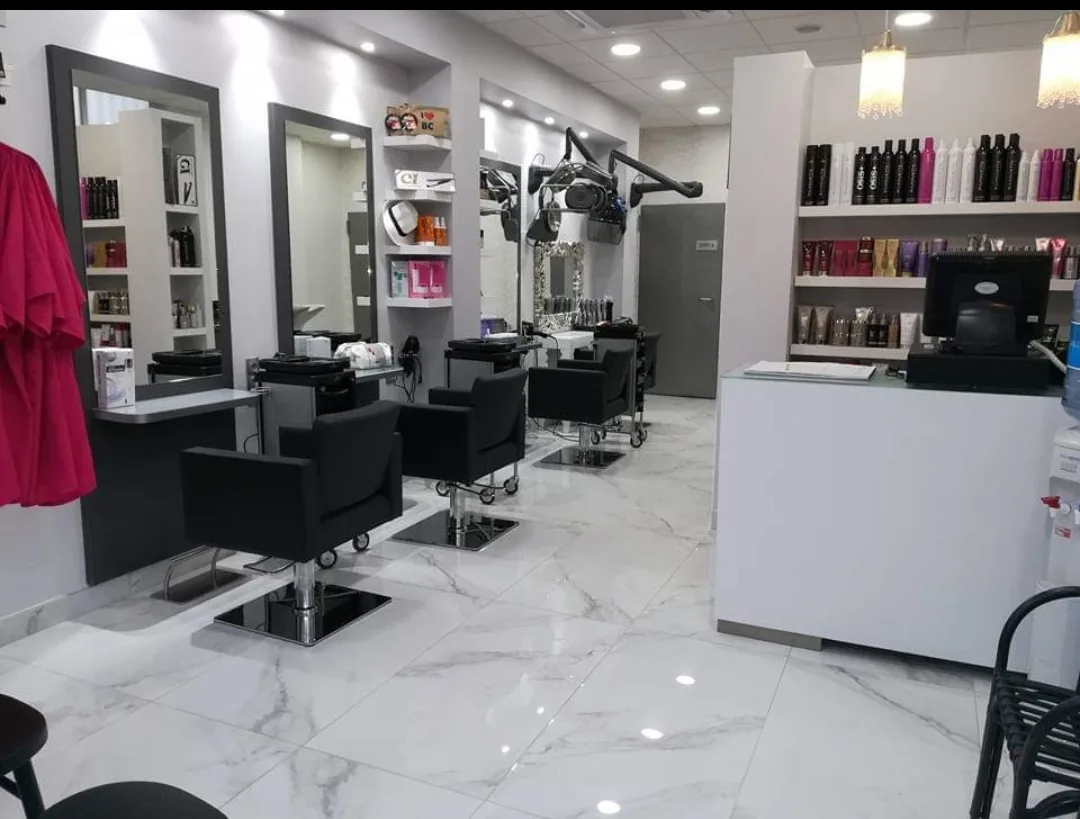 Interior del salón con suelo de mármol, sillones negros y expositor de productos